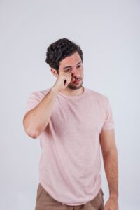 Hombre joven frotándose los ojos por molestias de ardor