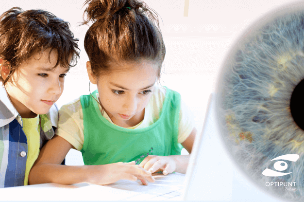 Niños usando ordenador con expresión concentrada, simbolizando el riesgo de miopía infantil por uso de pantallas.