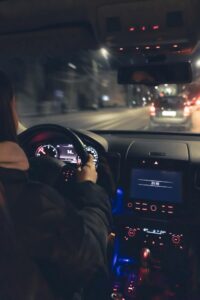 Mujer joven conduciendo de noche con dificultad para ver bien