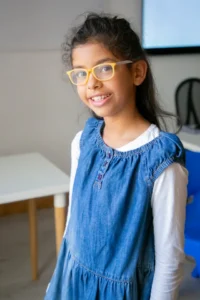 Niña de 11 años sonriente mientras utiliza gafas para corregir su estrabismo