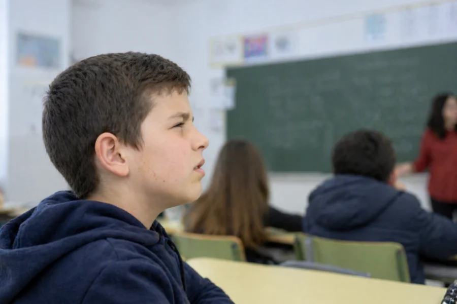 Niño en clase con dificultad para ver la pizarra y señales de miopía infantil
